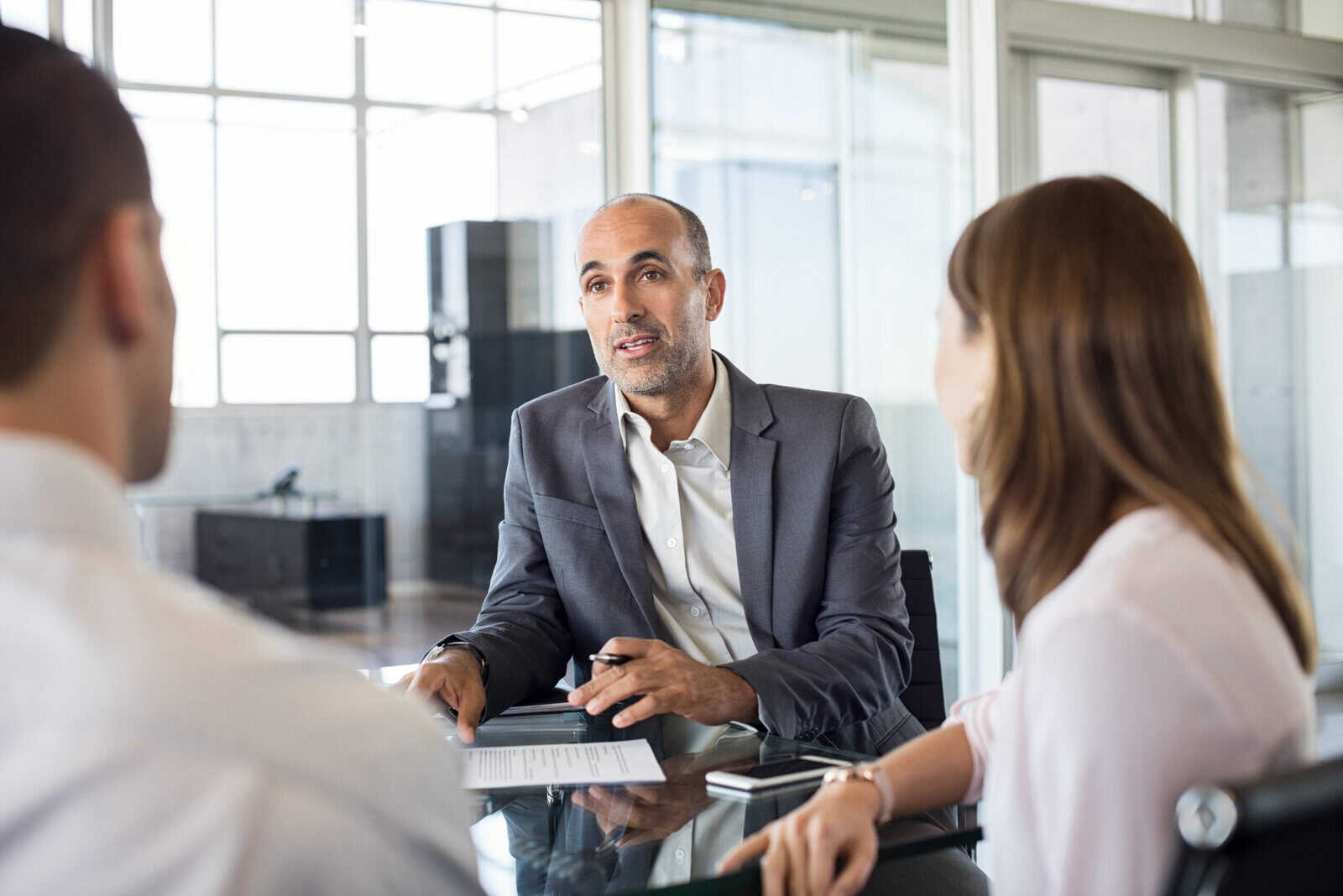 Financial planner discussing career options with a couple in a modern office setting – representing the financial planner vs analyst decision-making process