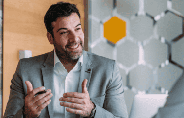 A financial advisor in a business meeting explaining the benefits of CFP certification to two clients in a modern office setting.
