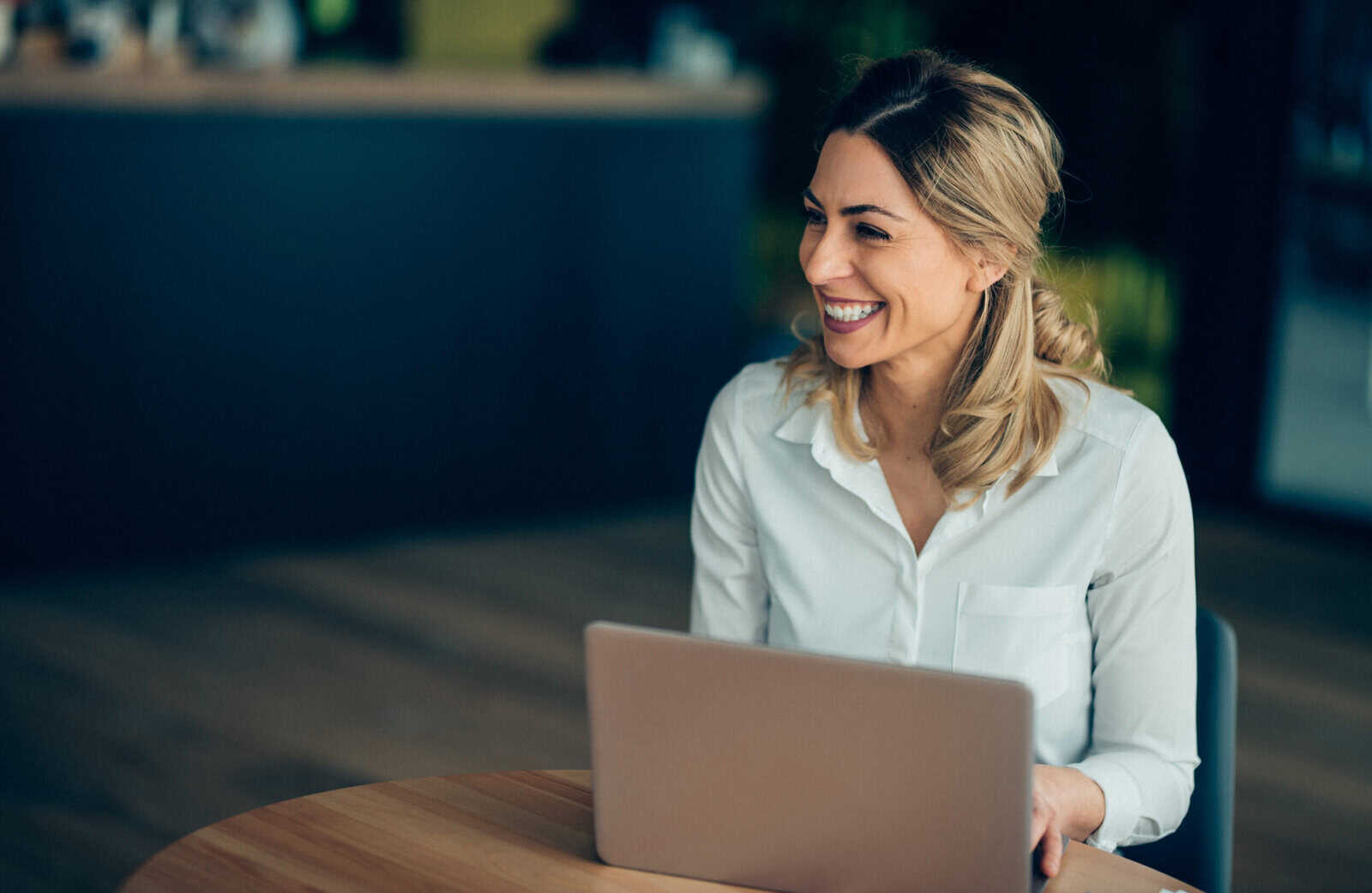 Smiling professional woman working on a laptop, representing career growth through CFP® certification with the Boston Institute of Finance