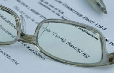 Close-up of glasses highlighting the One Big Beautiful Bill document, representing major tax changes for securities professionals