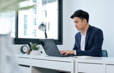 Professional studying for a securities exam prep course on a laptop in a modern office