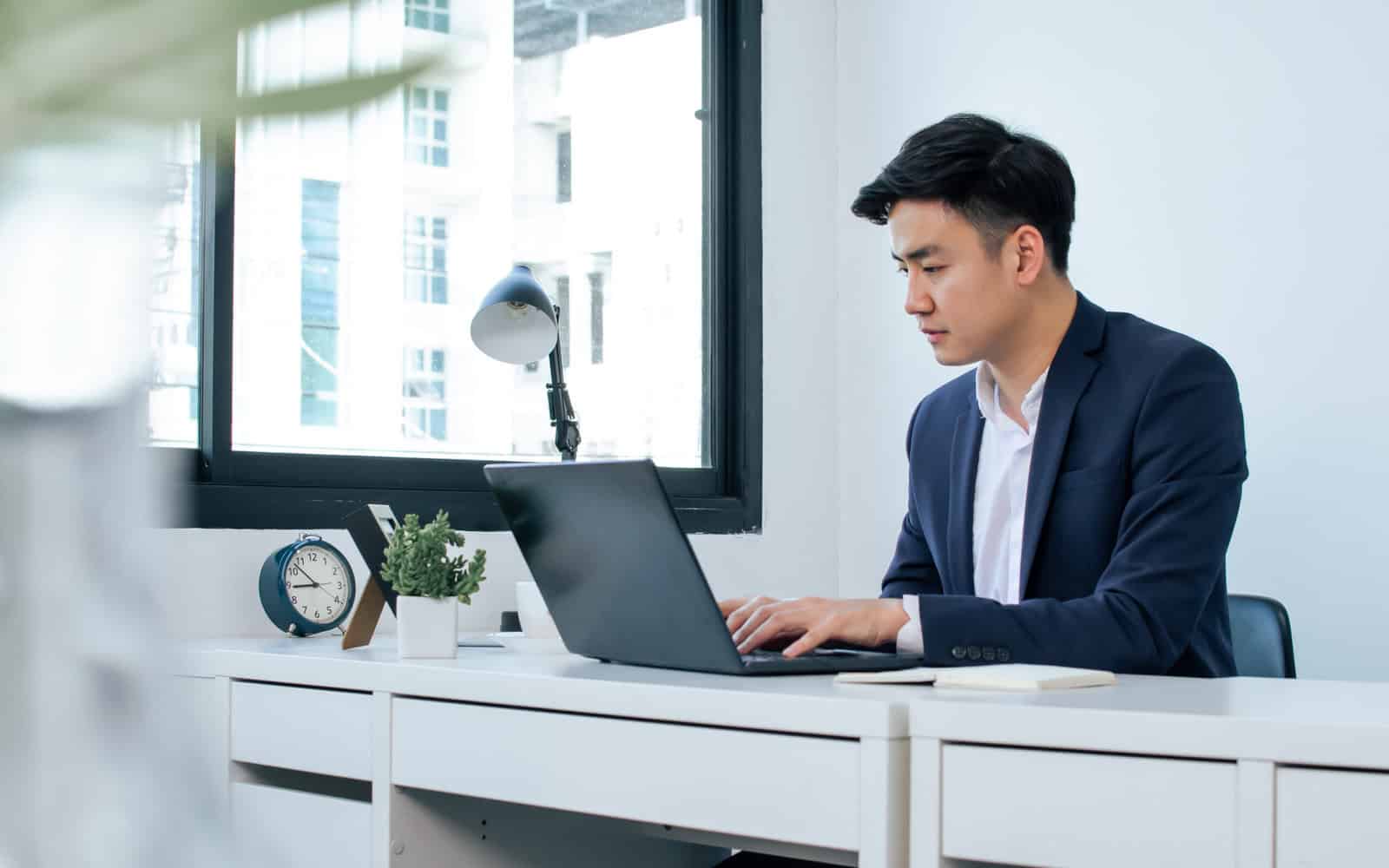 Professional studying for a securities exam prep course on a laptop in a modern office
