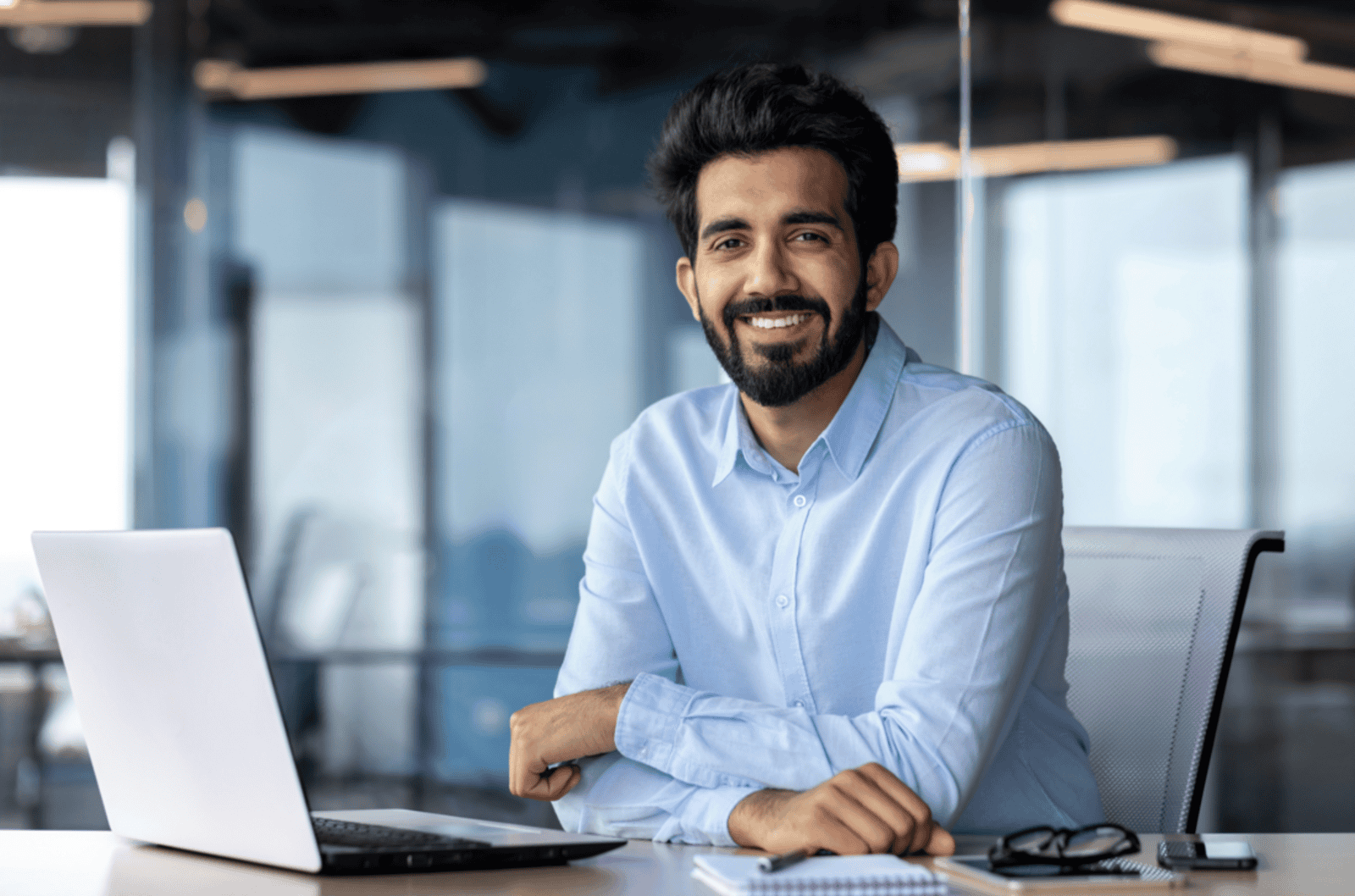 Smiling financial professional sitting at desk with laptop, representing IAR CE courses and continuing education for investment advisers.