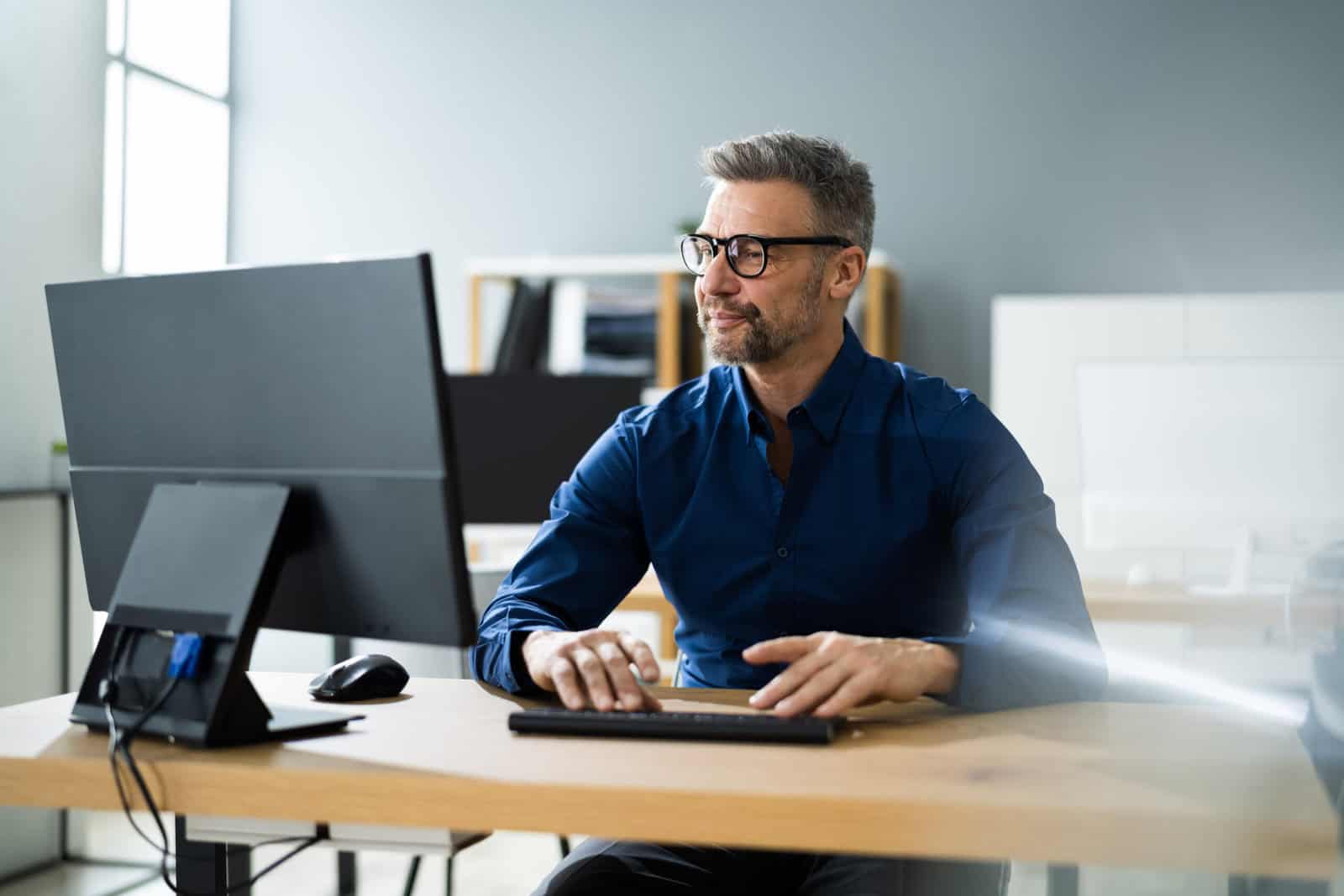 A professional studying at a computer in a modern office, representing someone preparing for the Series 66 exam and evaluating the best time to take it.