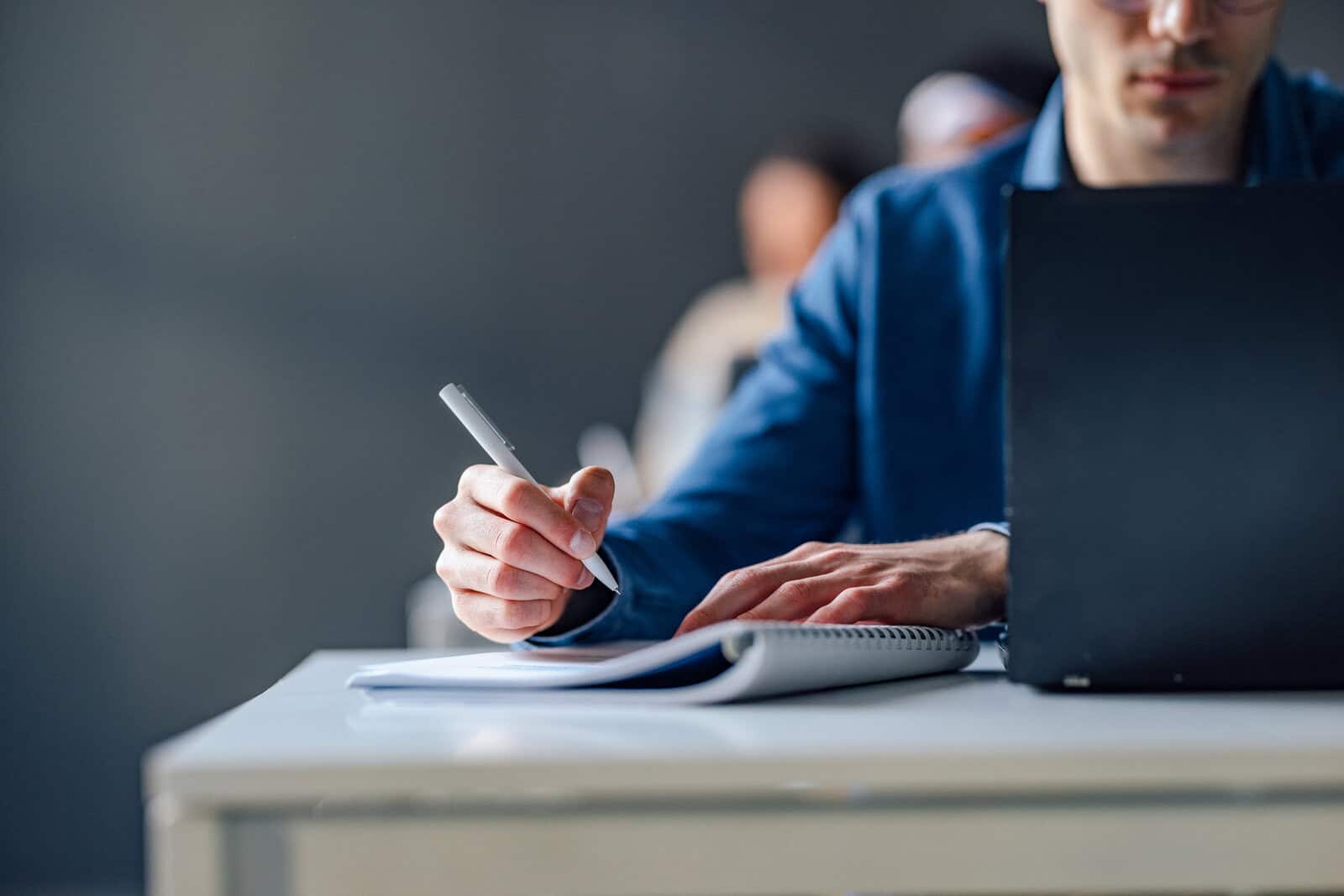 Professional studying for a FINRA qualification exam on a laptop and notebook, illustrating the updated FINRA exam retake waiting periods for SIE, Series 7, and other qualification exams.
