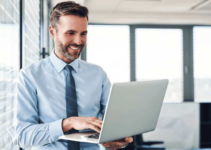 man smiling and using a laptop
